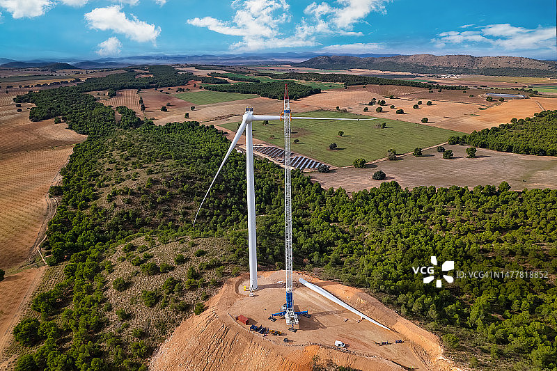 巨型起重机将风力涡轮机叶片吊起安装到在建风电场的机舱上，可再生能源，风能，西班牙图片素材