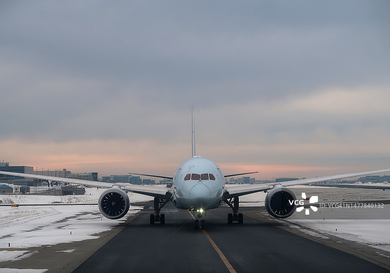 双引擎客机在日出时分的城市景观滑行道上图片素材