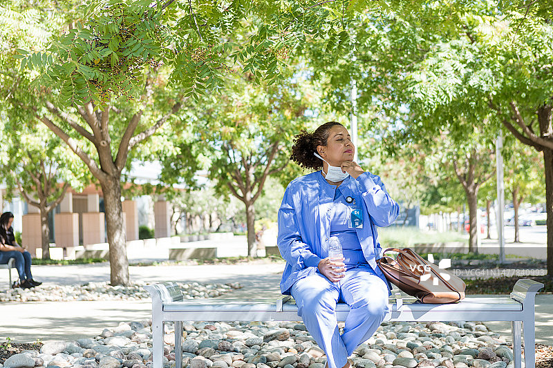 疲惫的女医生在医院外摘下口罩图片素材