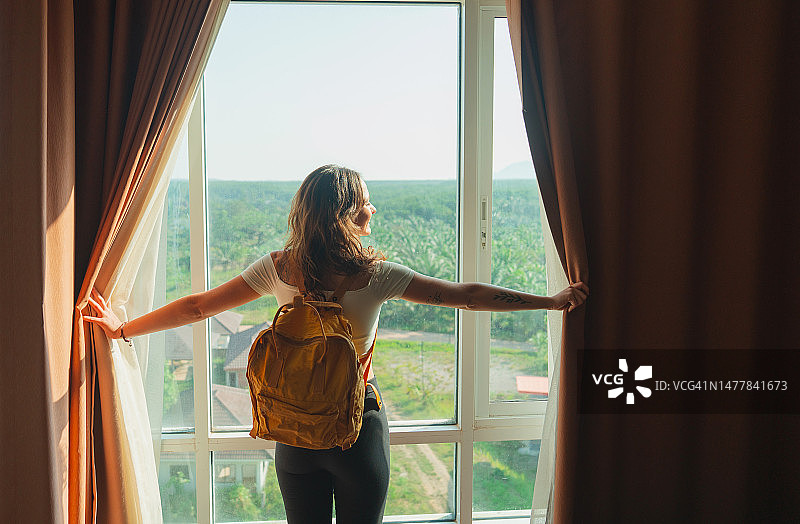 女人走进酒店房间透过窗户看丛林景色图片素材