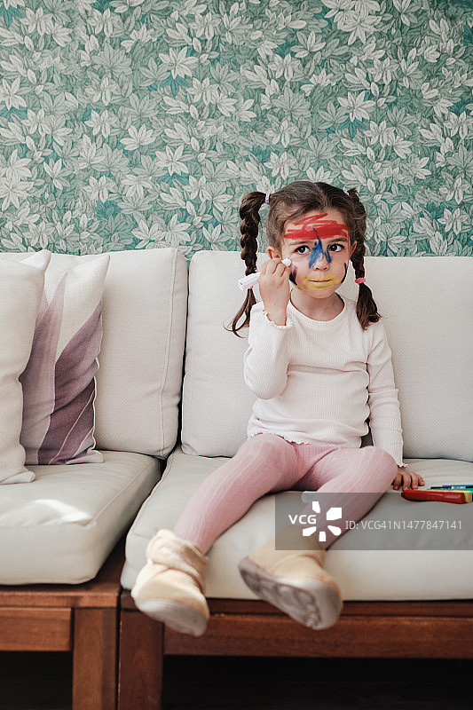 小女孩用颜料在脸上涂色图片素材