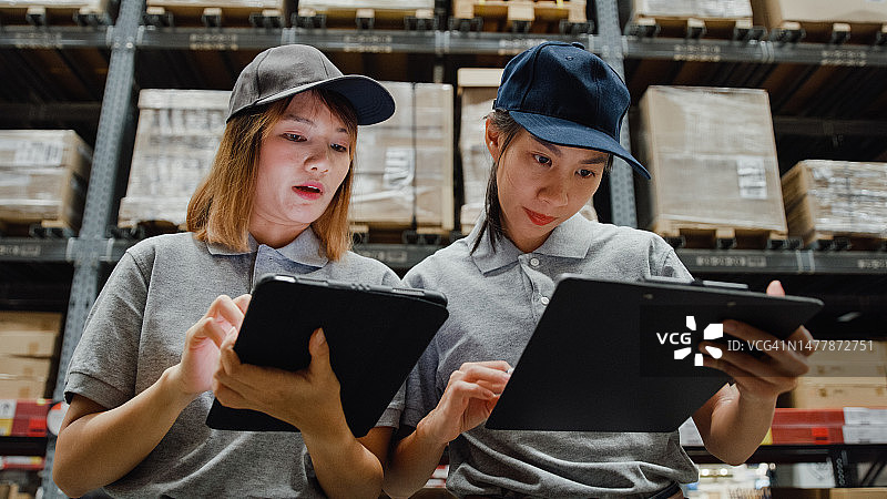亚洲女工人在仓库用平板电脑检查库存图片素材