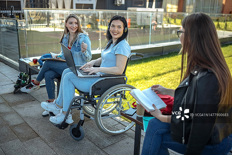 残疾大学生在户外与朋友共度时光和学习图片素材