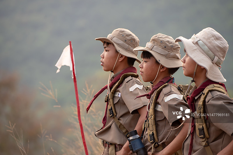 阳光明媚的日子里，穿着制服的美国童子军坐在绿色田野上，参加夏令营图片素材
