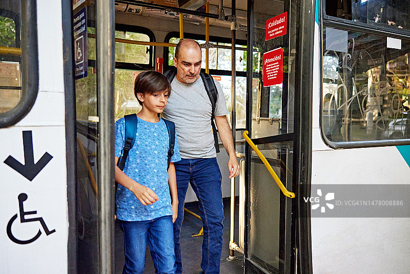 小男孩和中年男人从公共汽车后门下车图片素材