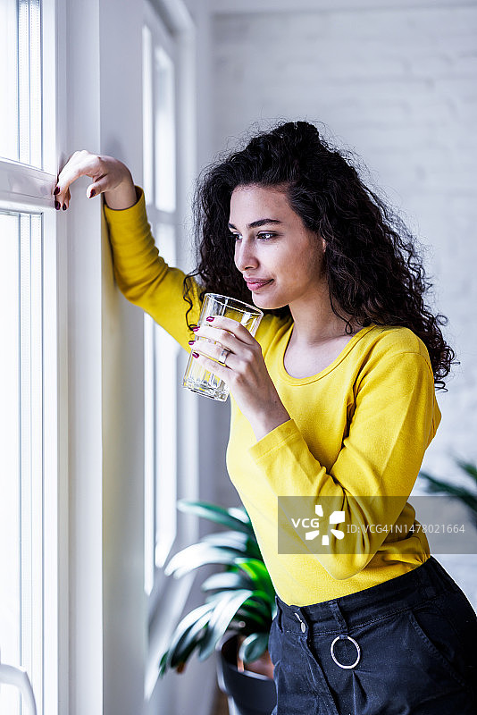 年轻女人感到口渴，正在喝一杯纯净的清水图片素材