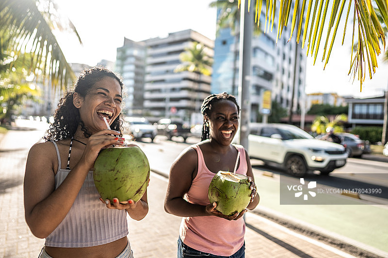 朋友们在木板路上喝椰子汁图片素材