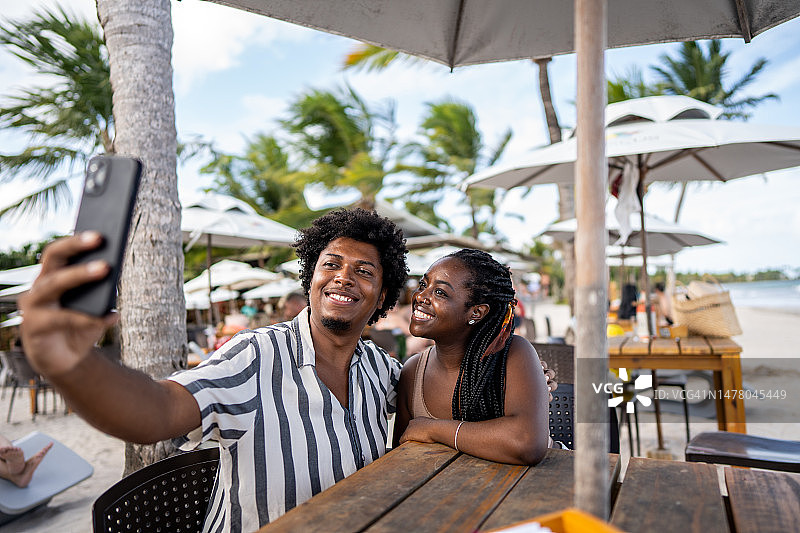 快乐的中年夫妇在海滩餐厅自拍图片素材