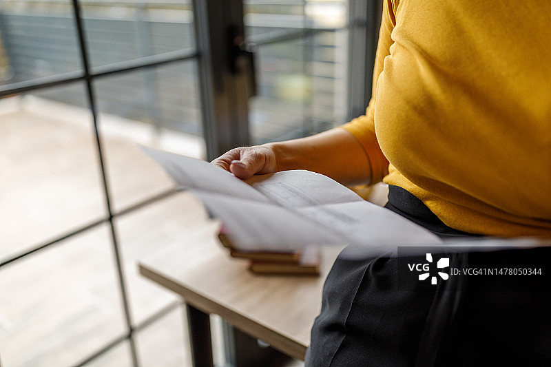 年轻女人在阅读账单，并与银行通电话图片素材