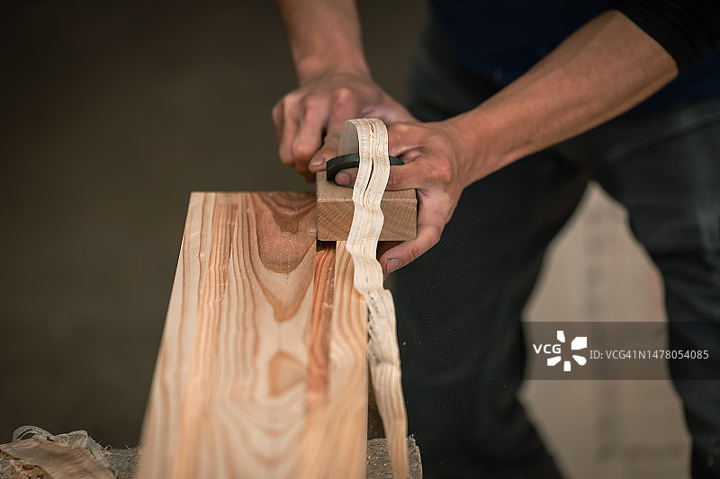 年轻木匠在车间手工加工木材，用于房屋建造图片素材