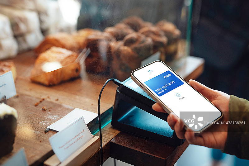 女人在咖啡馆用智能手机进行非接触式支付特写图片素材