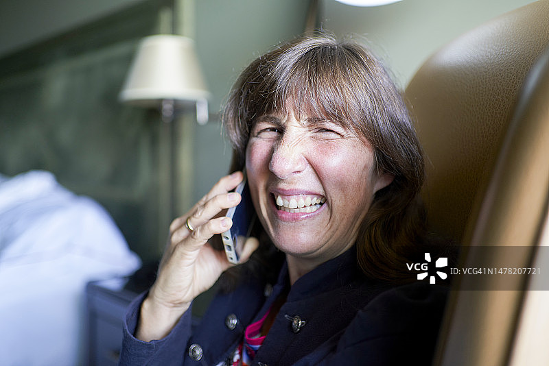 坐在椅子上打电话，对着镜头微笑的女人脸部肖像图片素材
