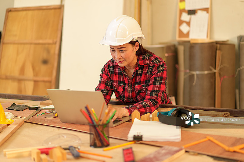 女木匠在木板上使用笔记本电脑特写图片素材