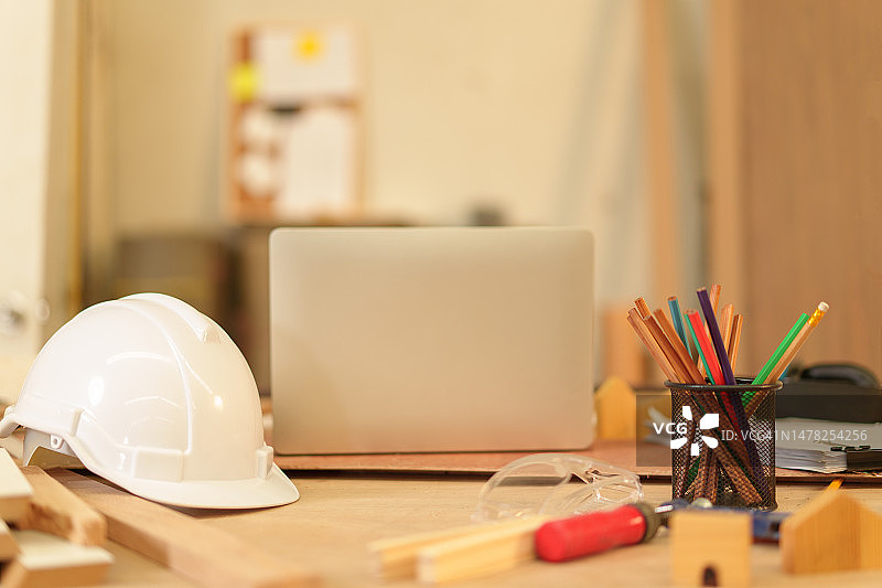 木板上的笔记本电脑、智能手机、写字板、笔、钉子、锤子、刨、锯、卷尺、水平仪、手套、眼镜、咖啡杯、锯末。木工。模型。建筑业务。图片素材