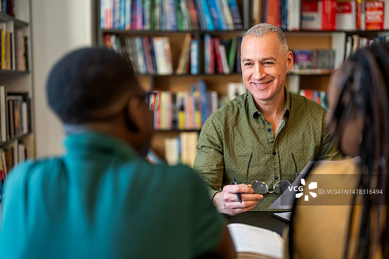 男导师在图书馆与大学生讨论图片素材
