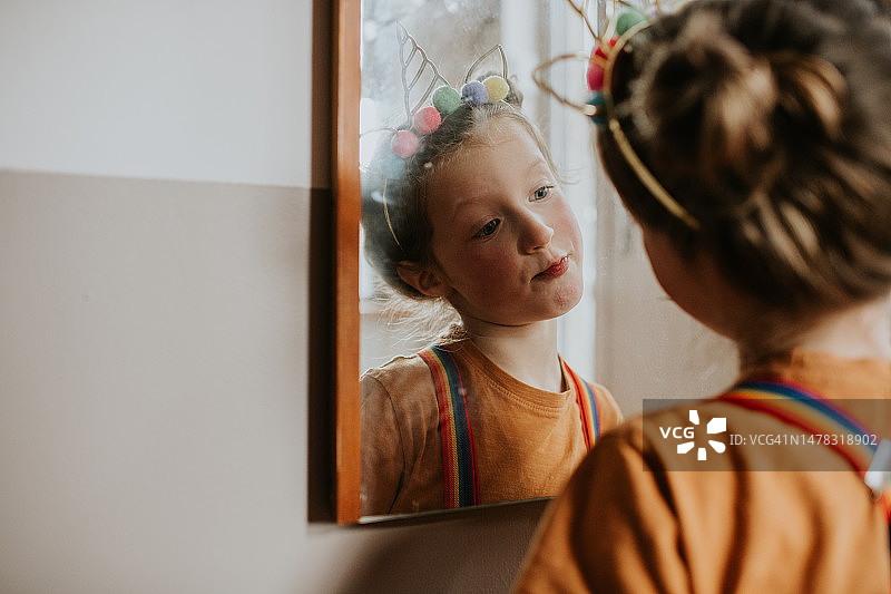 戴独角兽发箍彩虹牙套小女孩照镜子图片素材
