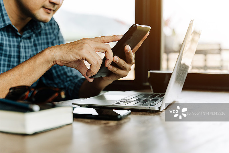 亚洲男人用智能手机和笔记本电脑进行在线转账或金融支付图片素材