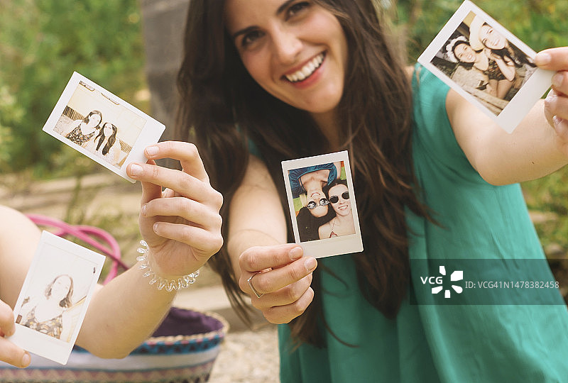 坐在地上用一次成像相机拍照的年轻女孩图片素材