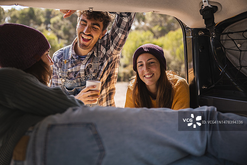 快乐的朋友们在露营车后备箱与女子交谈图片素材