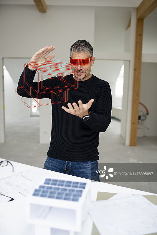 建筑师佩戴虚拟现实模拟器检查建筑工地的房屋模型图片素材