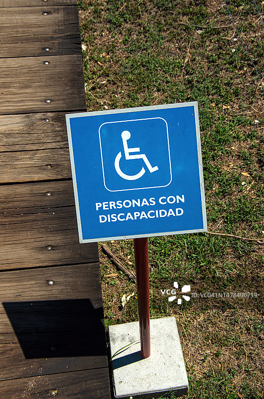 墨西哥瓦哈卡州阿尔班山考古遗址的木制轮椅坡道旁的西班牙语无障碍标志，上面写着“残疾人”图片素材