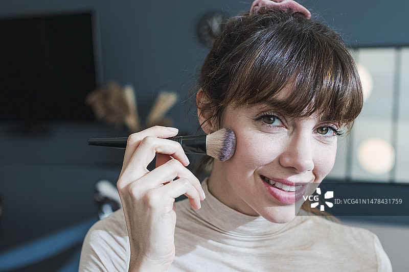 微笑的女人在家用刷子化妆图片素材