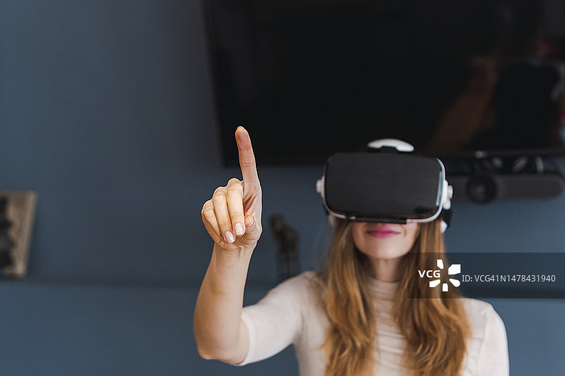 在家中佩戴VR头显并做手势的女人图片素材