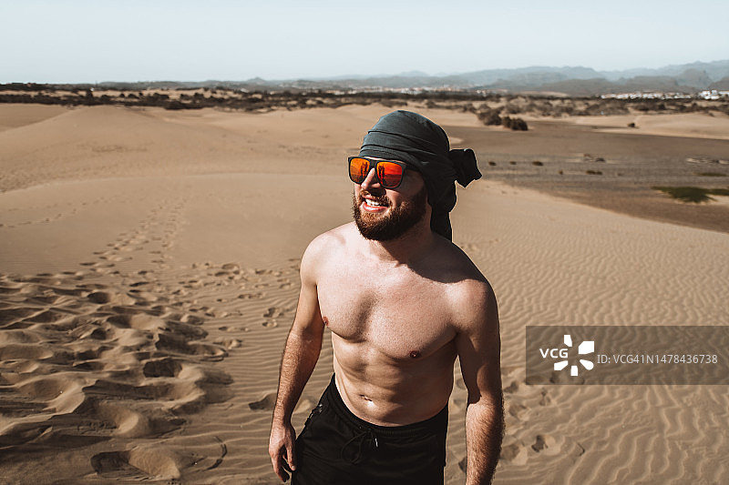 微笑的男人在西班牙大加那利岛马斯帕洛马斯沙丘顶上眺望大西洋图片素材