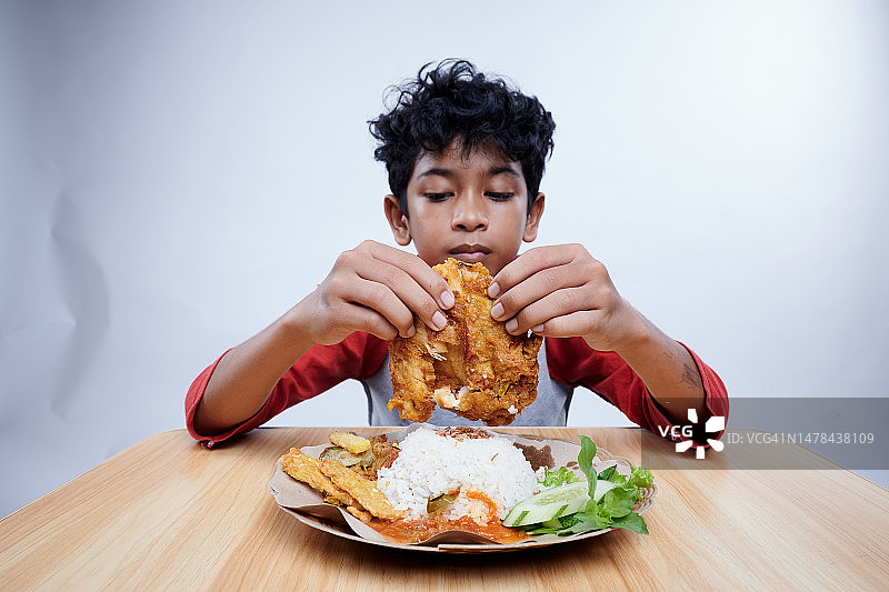 男孩吃炸鸡、米饭和蔬菜图片素材