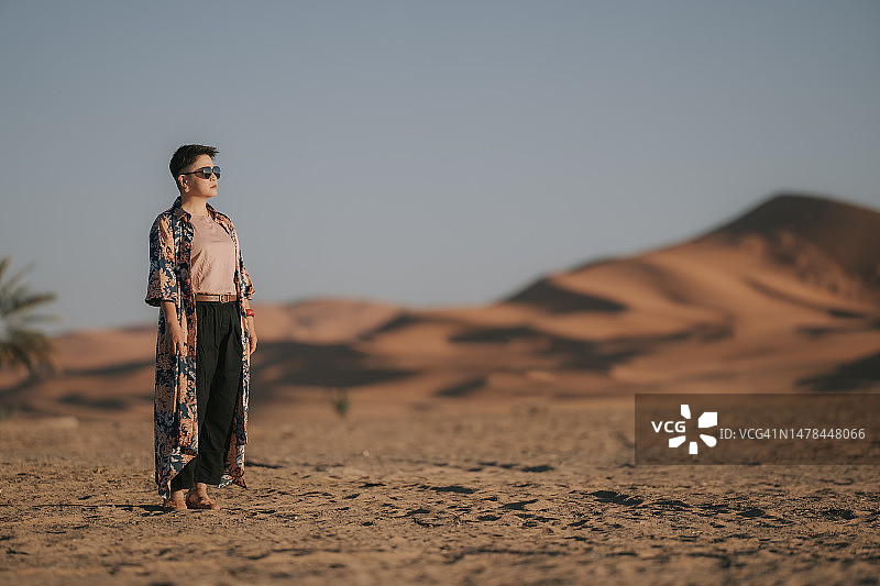 在撒哈拉沙漠的清晨眺望远方的亚裔中年妇女图片素材