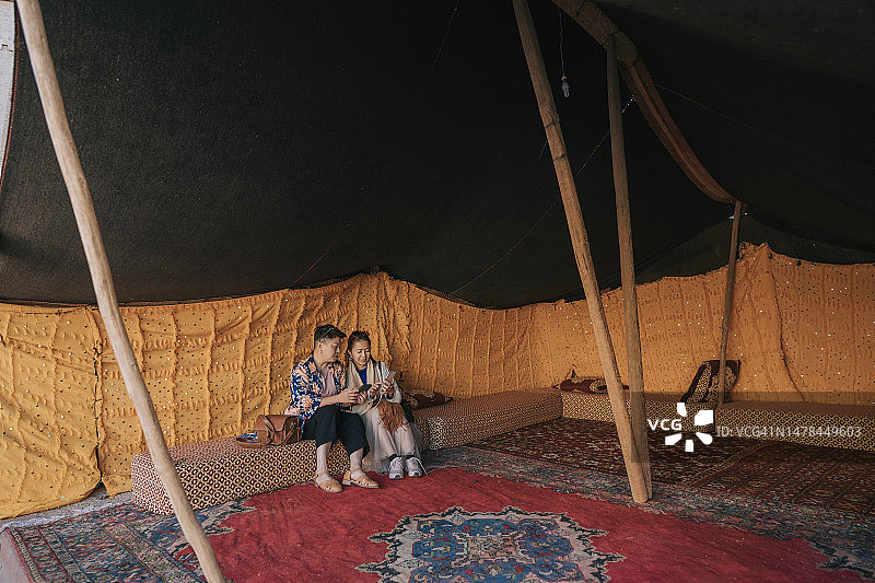 两位中国中年妇女在贝都因帐篷营地沙漠绿洲放松身心的广角拍摄图片素材