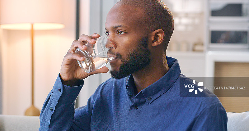 饮用水，补水，黑人男子坐在家中客厅的沙发上喝饮料图片素材