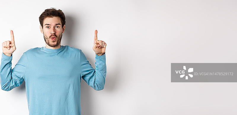 惊讶的年轻男子展示顶部广告，指着上面说着什么图片素材