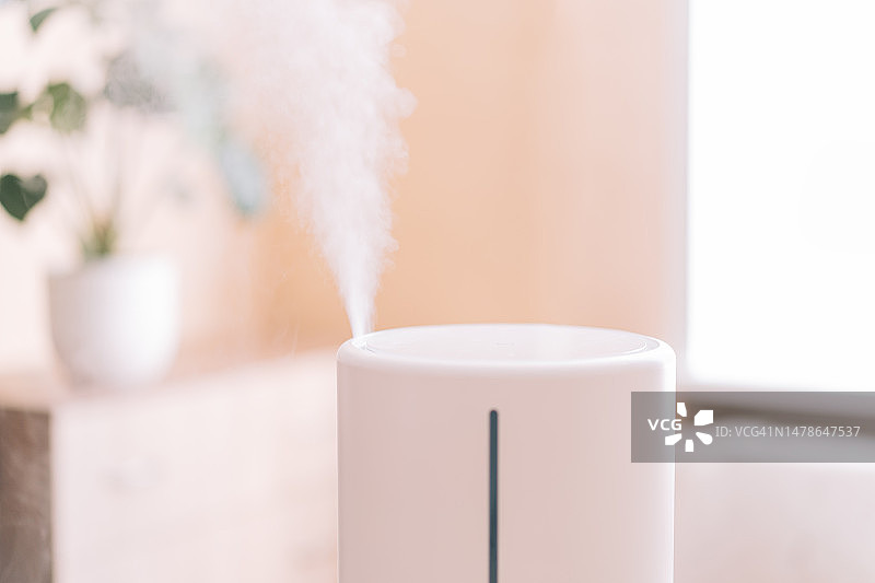 房间里的加湿器，在抽屉柜和窗户的室内植物对面图片素材