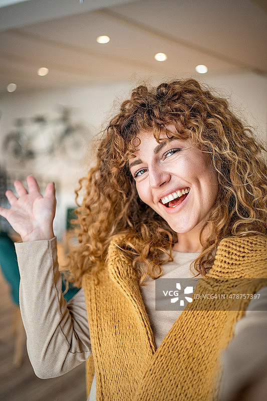 一位有着卷发的年轻漂亮女孩在最喜欢的咖啡店自拍图片素材