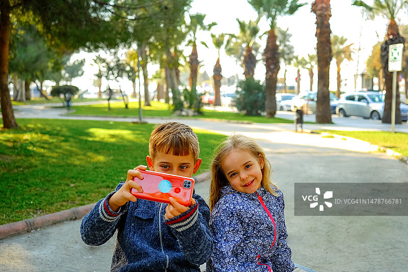 孩子们在城市公园用手机自拍图片素材