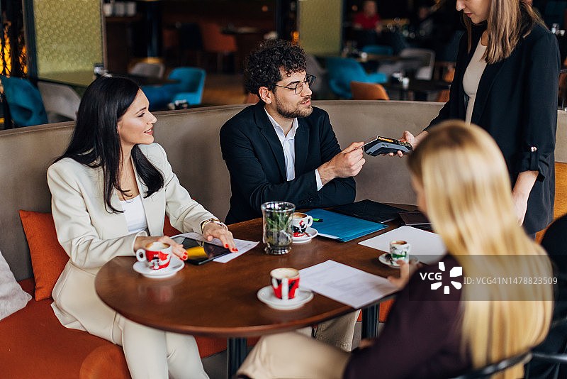 商务男士在咖啡店用信用卡进行非接触式支付图片素材