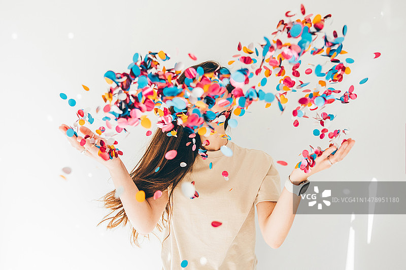 女子在白色背景下庆祝，洒落五彩纸屑图片素材