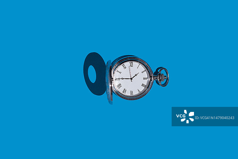 蓝色背景上的银色怀表：时间概念图片素材