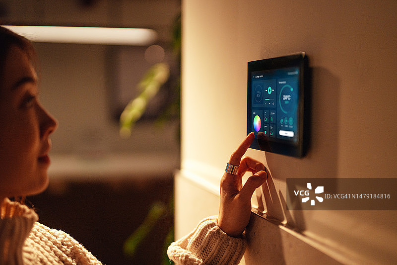 年轻女人使用智能家居设备激活家庭自动化系统图片素材