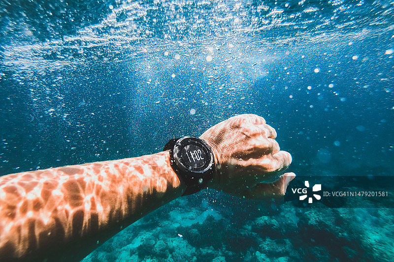 水下男子手上佩戴的防水智能手表：自由潜水活动图片素材