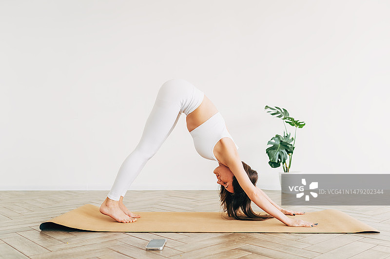 健康概念：年轻漂亮的女人在现代房间做瑜伽图片素材