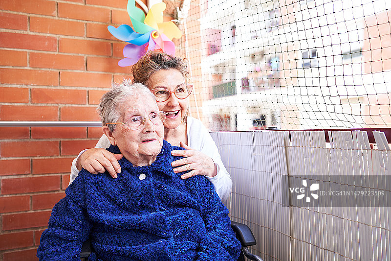 99岁老妇和女儿在阳台上欣赏风景图片素材