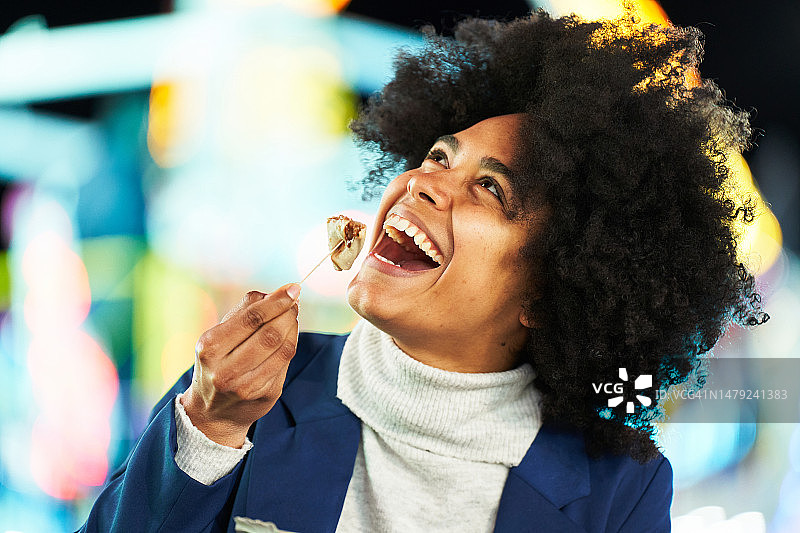 快乐的非洲女人在集市上吃巧克力薄煎饼图片素材