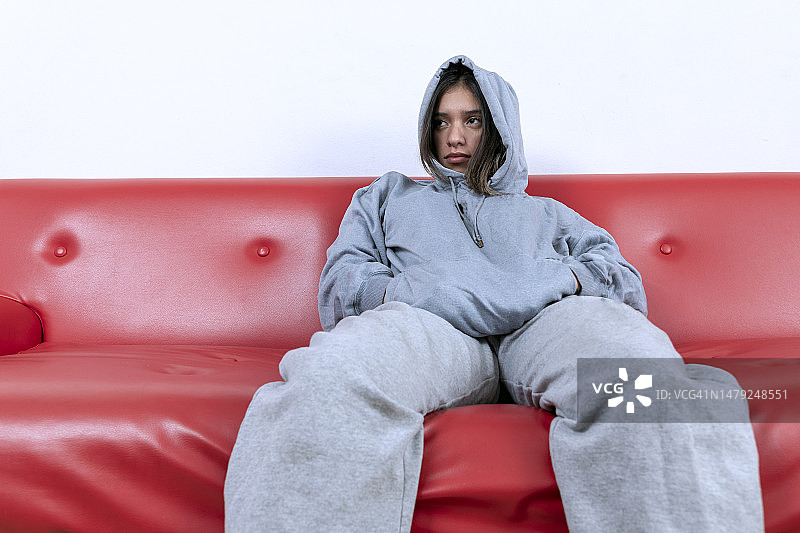 坐在红色扶手椅上，看向一侧的年轻墨西哥女子图片素材