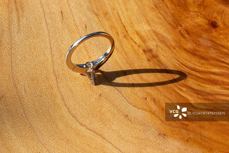 木桌上缺失主石的14K金订婚戒指，配有两颗闪亮的小钻石图片素材