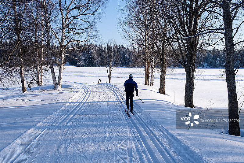 在芬兰凯努区卡亚尼奥卢湖冰冻湖面上滑雪的青少年男孩图片素材
