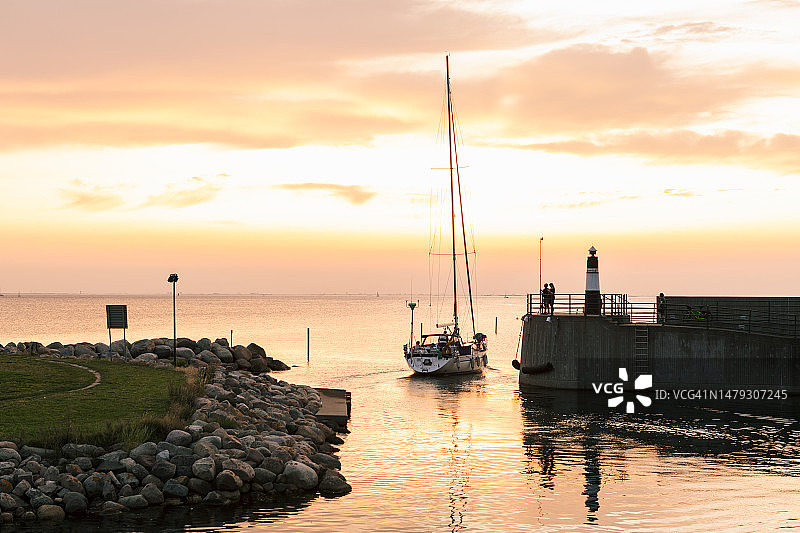 暮光中，海港入口处的一艘帆船图片素材