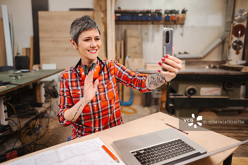 老年女木匠在木工车间工作时正在视频通话图片素材