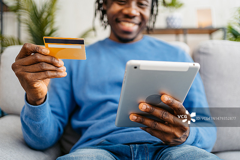 在家使用平板电脑在线购物的年轻男子图片素材